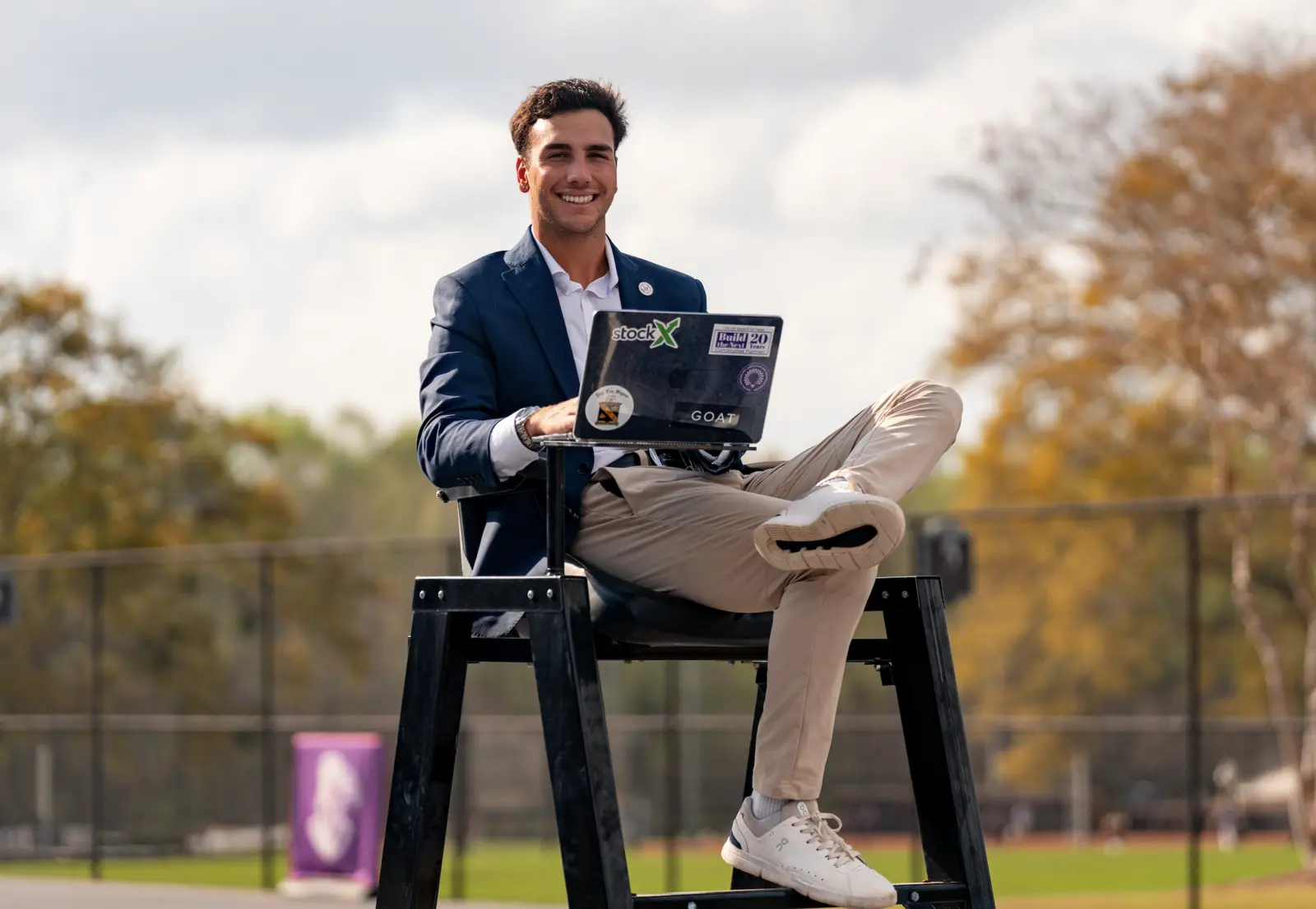 Elijah Poritzky seated courtside in a blazer with his laptop