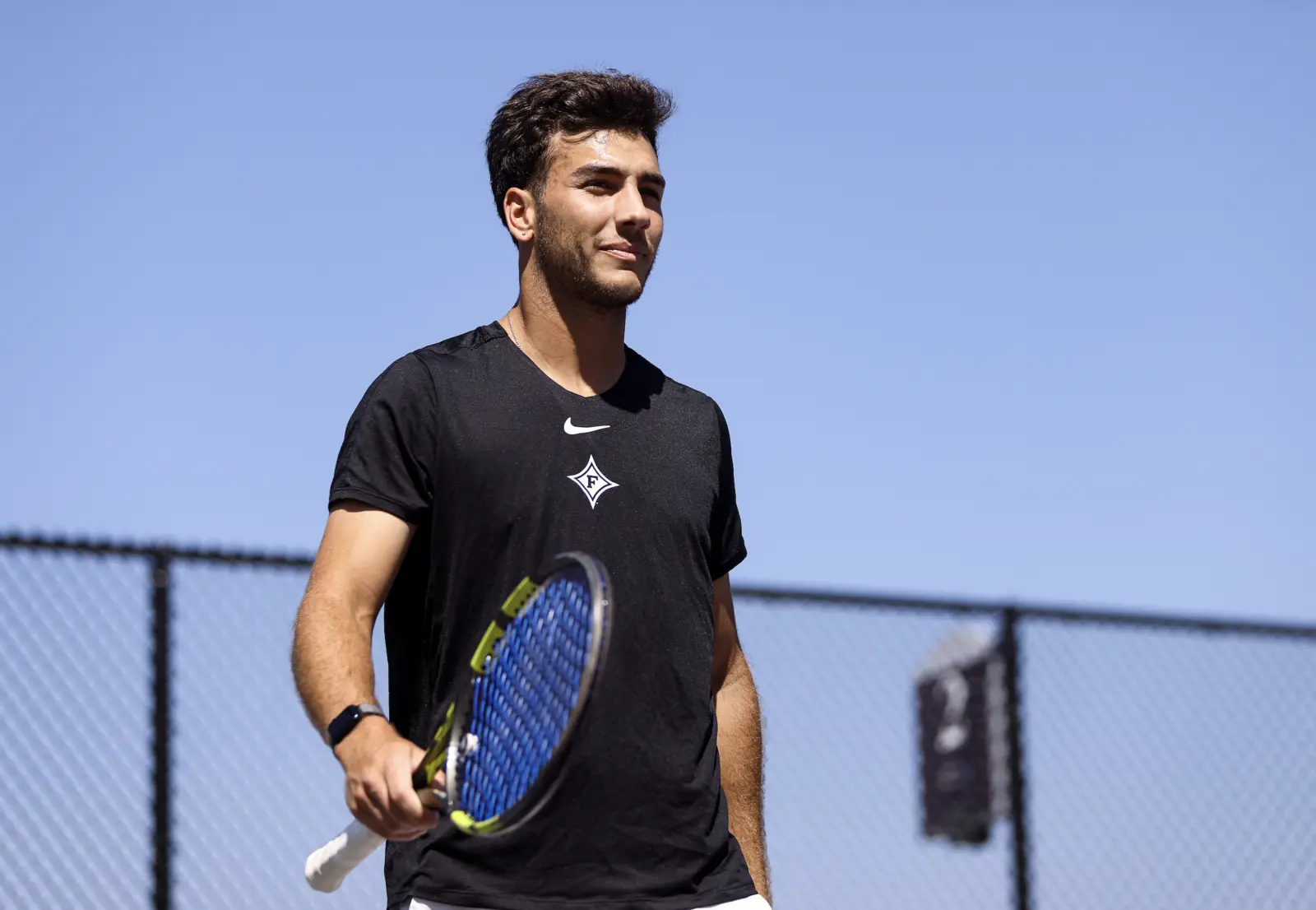 Elijah Poritzky holding his racket at the Furman tennis courts
