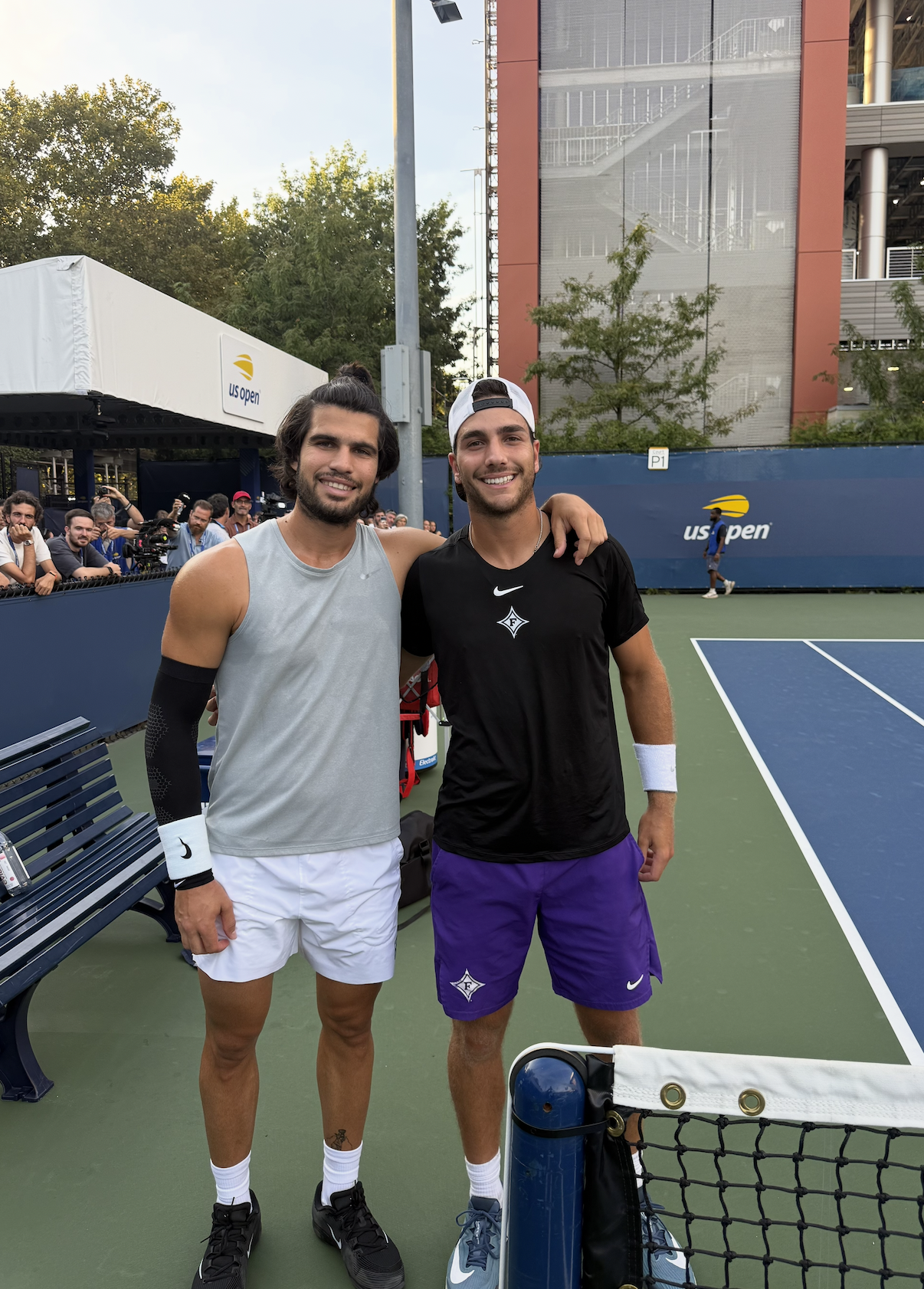 Two tennis players posing beside a practice court at the US Open